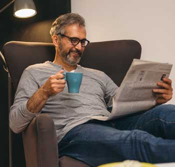 Man sitting in chair and reading newspaper