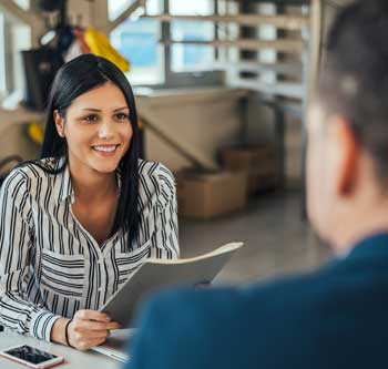 Woman in black and white striped shirt holding paperwork