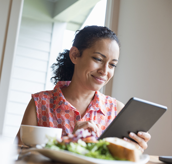 Woman in colorful shirt smiling at her tablet