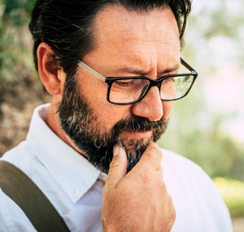 Man stroking his beard and looking down